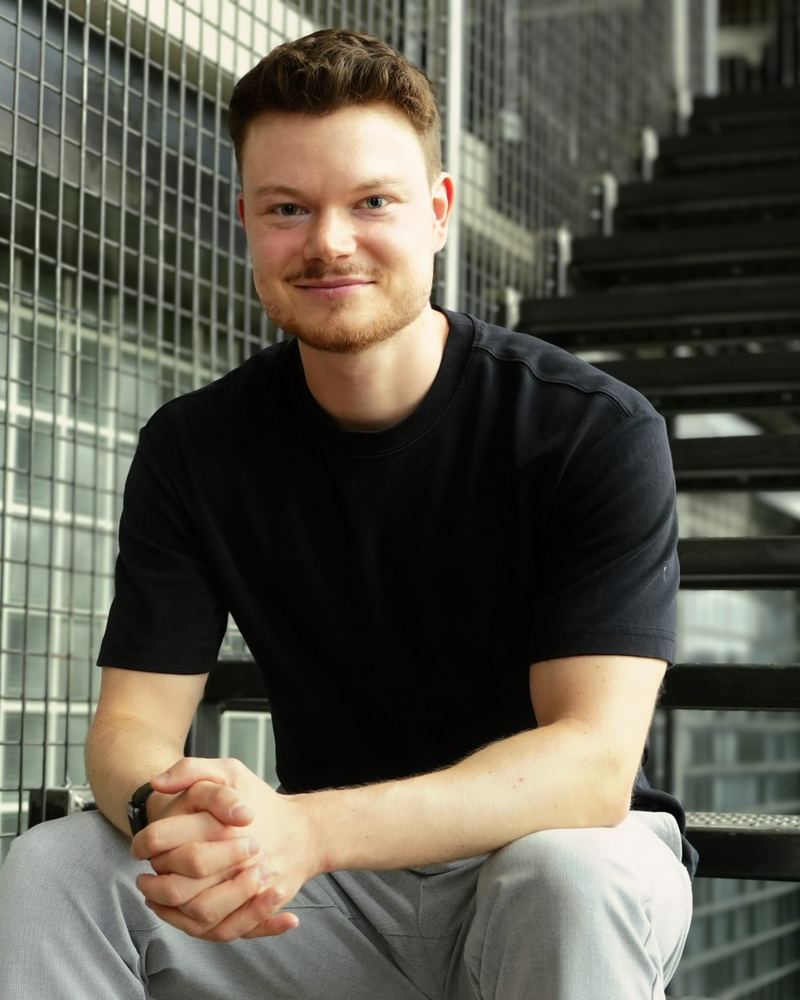 Patrick Starlinger, Co-Founder von nonoise.digital, sitzt lächelnd auf einer Metalltreppe